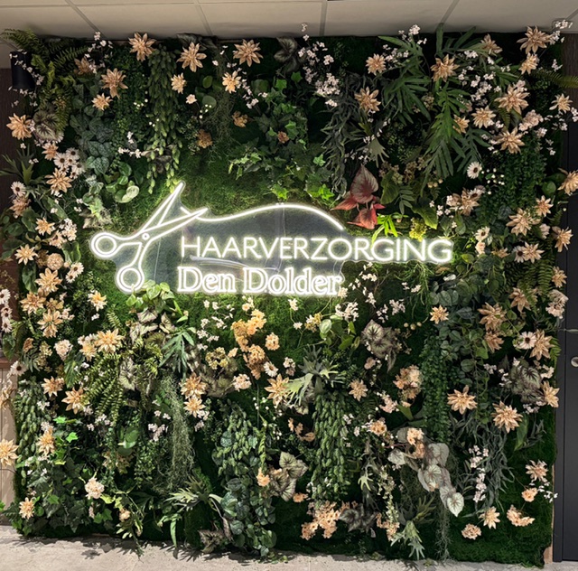 Bloemenwand met het logo van Haarverzorging Den Dolder